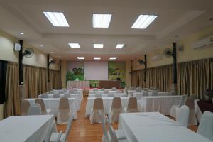 a room with white tables and chairs and a screen at Tokyo Country Inn in Nakhon Ratchasima