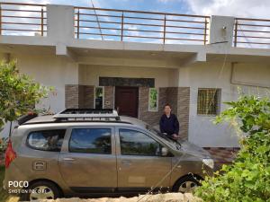 a man standing in front of a house with his car at Peacock Abode Farm in Bangalore