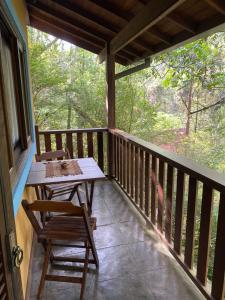 een houten veranda met een tafel en stoelen erop bij Havilá Arara Azul in Nova Friburgo