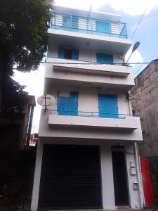a white building with blue doors and a balcony at dragon des iles in Pointe-à-Pitre