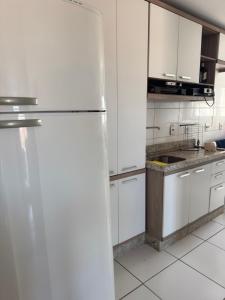 a kitchen with white cabinets and a refrigerator at Apartamento Pedra Branca in Palhoça