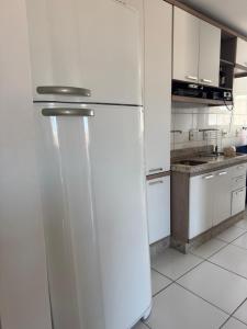 a kitchen with a refrigerator in a white kitchen at Apartamento Pedra Branca in Palhoça