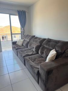 a brown leather couch in a living room with a window at Apartamento Pedra Branca in Palhoça