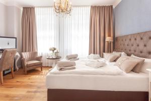 ein Schlafzimmer mit einem großen weißen Bett mit einem Kronleuchter in der Unterkunft freustil Boutique Hotel in Binz