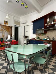 a kitchen with a large green table and chairs at Via Zara Arararooms in Palermo