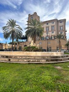 a statue in front of a building with palm trees at Via Zara Arararooms in Palermo