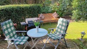 een tafel met twee stoelen en een bank met een grill bij Waldblick Nordhorn in Nordhorn