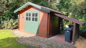 een bruin en groen schuurtje met een vuilnisbak bij Waldblick Nordhorn in Nordhorn
