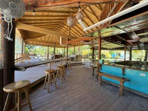 een houten terras met een bar en krukken bij Sea Eye Hotel - Laguna Building in Utila