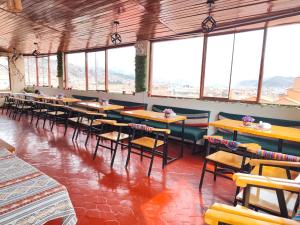 a dining room with tables and chairs and windows at SQ Estancia Del Inca in Cusco