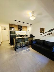 a living room with a black couch and a kitchen at Go Eco Paradise Ap210 Pé na Areia e Piscina no Centro do Cumbuco in Caucaia
