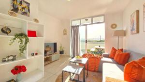 a living room with a couch and a tv at Steps from the beach , Muizenberg home in Muizenberg