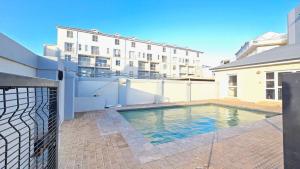 a swimming pool in front of a building at Steps from the beach , Muizenberg home in Muizenberg
