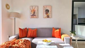 a living room with a gray couch with orange pillows at Steps from the beach , Muizenberg home in Muizenberg +20 photos