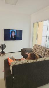 een persoon die op een bank ligt en een mobiele telefoon vasthoudt bij Dúplex Lagoa in Paracuru