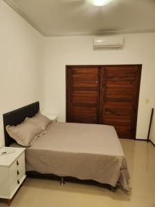 a bedroom with a bed and a wooden door at Dúplex Lagoa in Paracuru