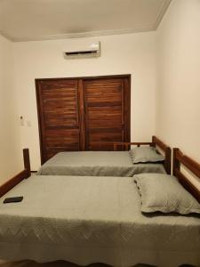 a bedroom with two beds and a wooden door at Dúplex Lagoa in Paracuru