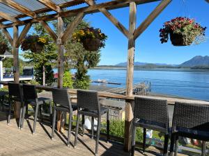 a table and chairs on a deck with a view of the water at Tofino Paddlers Inn in Tofino