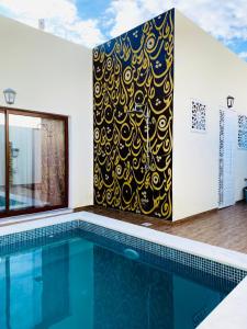 een zwembad met een muurschildering op een muur ernaast bij Villa Sabrina in Awlād ‘Umar