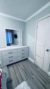 a white bedroom with a dresser and a mirror at Explore Rooms JFK in Locust Manor