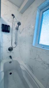 a white bath tub in a bathroom with a window at Explore Rooms JFK in Locust Manor +14 photos