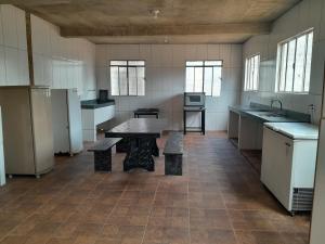 eine große Küche mit einem Tisch und Bänken darin in der Unterkunft Sítio Eventos Nossa Senhora Aparecida in São Joaquim de Bicas