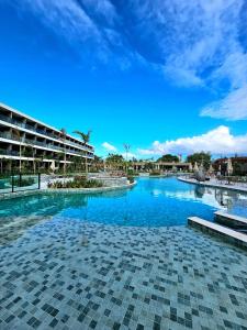 a swimming pool in a resort with a blue sky at Luxuoso e sofisticado Beach Class Verano by HM in Ipojuca