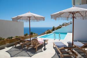 a child sitting in a chair on a patio with umbrellas at Althea Anafi Suites in Anafi