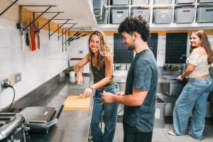 a man and two women standing in a kitchen cutting a cake at Mad Monkey Potts Point in Sydney