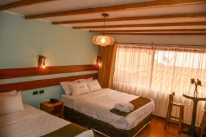 una camera d'albergo con due letti e una finestra di Hotel Boutique MIRANDO AL SOL a Ollantaytambo