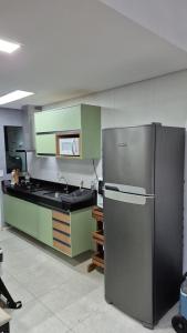 een keuken met groene kasten en een roestvrijstalen koelkast bij Morada do Toque - Encantos de Milagres in São Miguel dos Milagres
