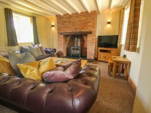 a living room with a leather couch and a fireplace at 1 Clarkes Lane in Oswestry