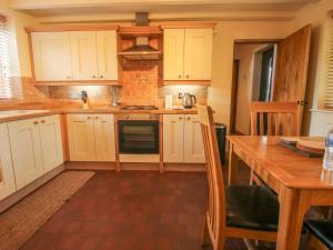 a kitchen with white cabinets and a wooden table at 1 Clarkes Lane in Oswestry