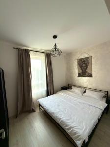 een slaapkamer met een bed met witte lakens en een raam bij Cleo Residence 3 Ghiroda in Ghiroda