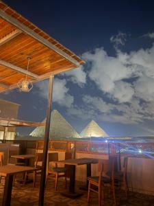een uitzicht op de piramides vanuit een restaurant met tafels en stoelen bij Cheristo pyramids view inn in Caïro
