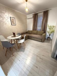 een woonkamer met een bank, een tafel en stoelen bij Cleo Residence 4 Ghiroda in Ghiroda