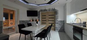 a kitchen with a white table and black chairs at Apartament u Krupy z Prywatnym Jacuzzi i tarasem Widokowym in Murzasichle
