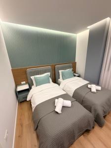 two beds in a room with towels on them at LUX Apt Korca in Korçë