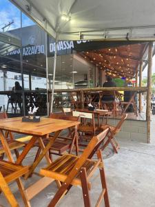 een groep houten tafels en stoelen voor een restaurant bij Hotel e Conveniência G3 in Teixeira de Freitas
