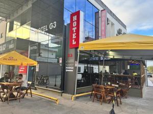 a group of tables and chairs in front of a building at Hotel e Conveniência G3 in Teixeira de Freitas