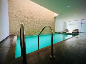 a swimming pool in a building with two chairs at Luxury City Suites in Guayaquil