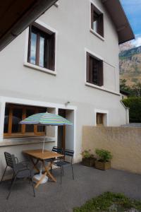 einen Tisch und Stühle mit einem Regenschirm vor einem Gebäude in der Unterkunft Au Coeur Des Ecrins in LʼArgentière-la-Bessée