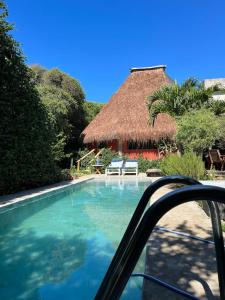 a swimming pool with a straw hut in the background at Oca House in Búzios