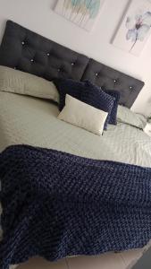 een bed met een blauwe deken en kussens erop bij Hotel Gayra in Antofagasta