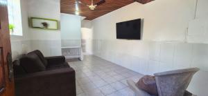 a living room with a couch and a tv on a wall at STO01 - Casa ampla em bairro tranquilo do Guarujá in Guarujá