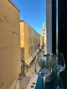 two wine glasses sitting on a table looking out a window at Central View Zadar in Zadar