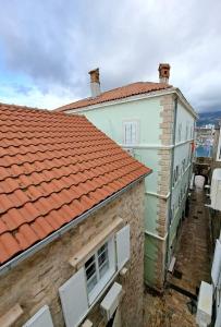 a white building with a red roof and white chairs at Old town nest in Budva