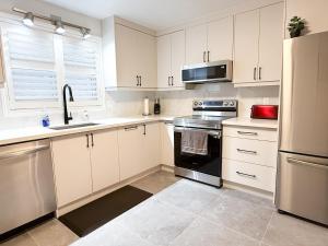 een keuken met witte kasten en een roestvrijstalen koelkast bij The Promenade Cottage License # 002-2023 in Niagara on the Lake +35 foto's