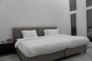 een slaapkamer met een groot bed met witte lakens en kussens bij Masfout Mountains View in Sinādil +33 foto's