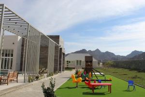 een speeltuin met kleurrijke stoelen op een groen gazon bij Masfout Mountains View in Sinādil
